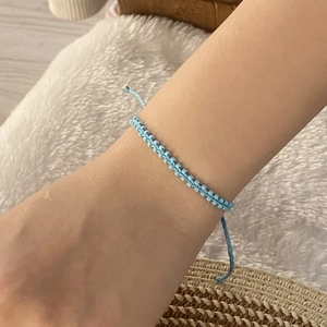 Bohemian light blue seed bead woven bracelet displayed on wrist with aesthetic background