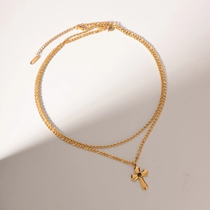 Macro detail of gold-plated double-layer necklace with textured cross pendant and Figaro chain