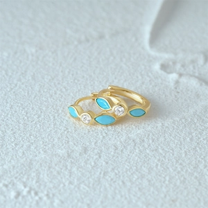 Close-up of gold turquoise hoop earrings with marquise-cut gems and sparkling zircons