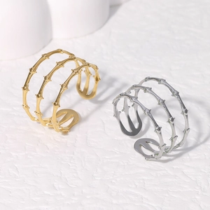 Detailed view of layered gold and silver bamboo knot open rings on a textured surface