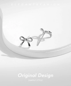 Elegant s925 silver bow stud earrings shown in a minimalist still life photography style