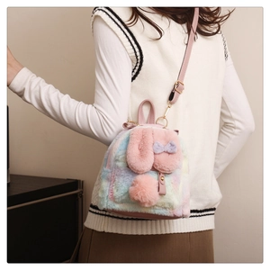 Detail of colorful tie-dye plush bunny backpack with long ears and pink bow accessory
