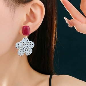 Détail de boucles d'oreilles fleur à pois noirs et blancs portées par un mannequin