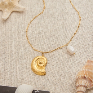 Détail du pendentif nautile en or 18K avec perle d'eau douce sur lin beige