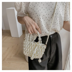 Détail du sac à main en perles avec un nœud en satin de soie et une bandoulière perlée