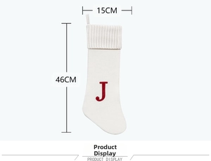 Detail view of large white knitted Christmas stocking with red letter J embroidery