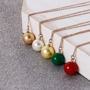 Cinq colliers avec pendentifs perles colorées en acier titane or rose sur bloc bois