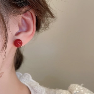 Close-up of minimalist gold-plated red ball stud earrings worn by a model