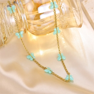 Detail of mint green butterfly pendants on elegant gold-plated chain over silk