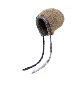 Détail du bonnet en peluche kaki avec bordures en tricot bleu et blanc et longues lanières