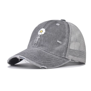 Detailed close-up of distressed brim on washed cotton baseball cap with mesh back