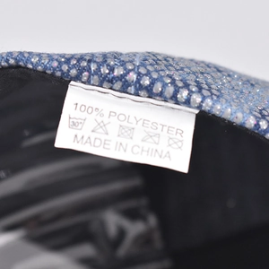 Detailed macro view of blue rhinestone baseball cap interior with 100% polyester wash label