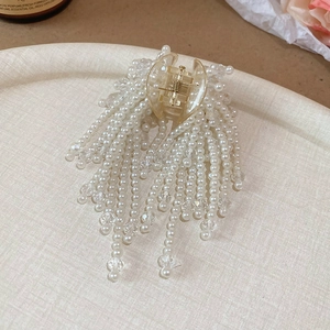 Macro detail of artificial pearls and crystal tassels on a transparent resin hair claw clip
