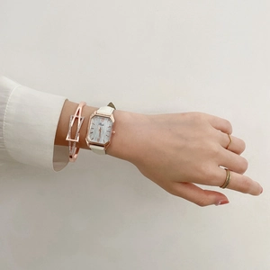 Elegant woman wearing a rose gold rectangular watch with a white leather strap and bracelet