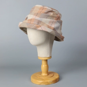 Detail of vintage plaid bucket hat with textured orange and brown fabric on stand