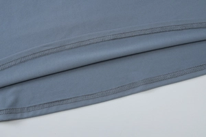 Close-up detail of double-needle stitching on gray-blue knitted fabric dress