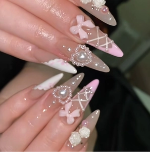 Detail of pink and white press-on nails with 3D pearls, bows, and camellia flowers