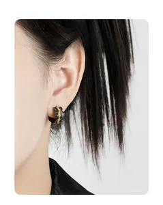 Close-up of C-shaped mixed-metal stud earrings with black volcanic texture on model