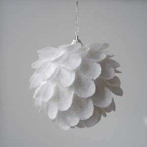 Close-up of a white petal-shaped Christmas ball with glitter texture and silver loop