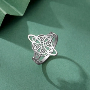 Detail shot of Celtic knot stainless steel ring with intricate cutout patterns on green paper