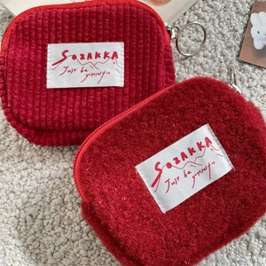 Detail of red corduroy and fluffy fleece pouches with zip puller and woven label