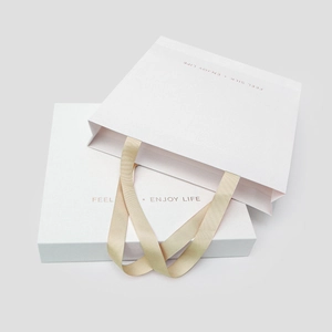 Elegant white silk gift box and textured paper bag with champagne ribbons for travel set
