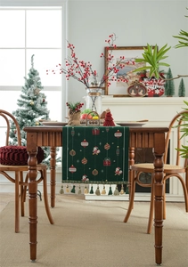 Detail of green Christmas table runner with jacquard holiday patterns and hanging tassels
