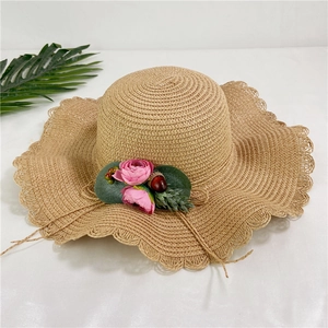 Vue détaillée d'un chapeau de paille avec fleurs roses et bordure ondulée