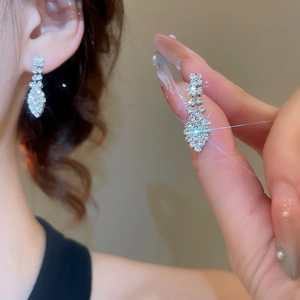 Close-up of sparkling silver tassel earrings with diamond drops worn by a model