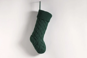 Close-up of dark green knitted Christmas stocking with classic diamond pattern texture