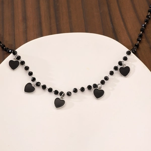 Detail of gothic beaded necklace featuring five black heart pendants on a display tray