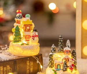 Detailed view of LED glowing Christmas resin miniature houses with snowmen and pine trees