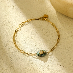 Close-up of 18K gold stainless steel bracelet with green stone and star pendant
