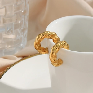 18K gold plated stainless steel chunky twist hoop earrings on a white ceramic mug