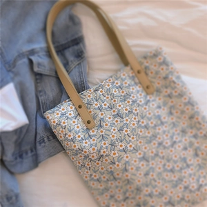 Détail du sac cabas floral avec poignées en cuir et rivets métalliques robustes