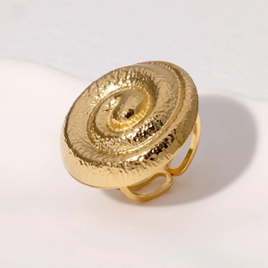 Detailed view of gold spiral ring featuring a modern hammered texture on a white plate