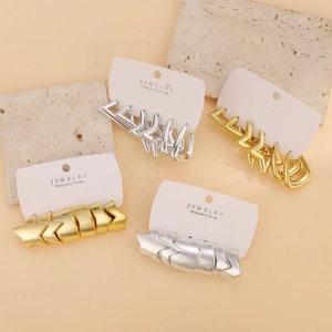 Close-up of gold and silver C-shaped star earrings on stone background