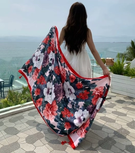 Detail of floral beach shawl with red tassels showing fabric texture and vibrant prints