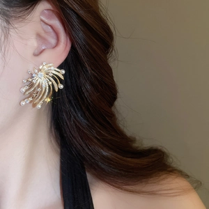Detailed close-up of firework star earrings with pearls and zircon stones on ear