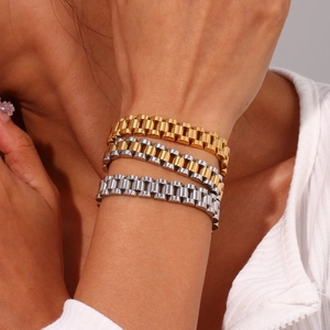 Dettaglio di tre braccialetti stile cinturino in oro, argento e bicolore in acciaio inox