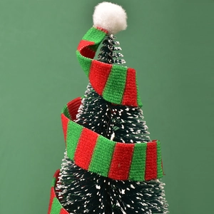 Nahaufnahme von Mini-Christbaumschmuck mit Schneeeffekt und gestreiftem Stoffband