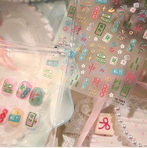 Detail of Mahjong themed nail stickers with gold foil characters and floral patterns