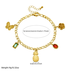Detailed view of gold bracelet with butterfly, pineapple, and emerald drop charms