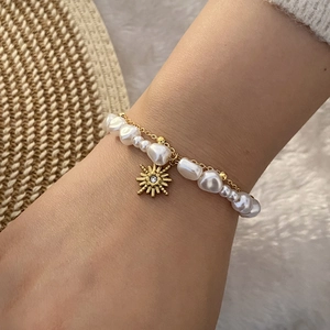 Close-up of double-layer bracelet with baroque pearls and gold sun pendant
