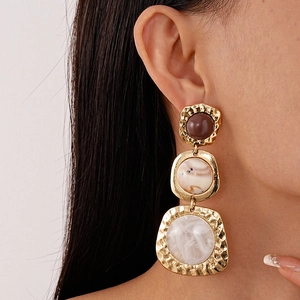 Detail of vintage gold earrings with resin geometric pendants on model side profile