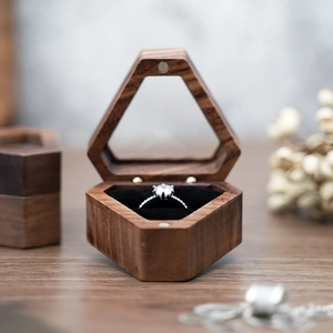 Detail of a vintage hexagonal walnut ring box with a silver diamond ring on velvet