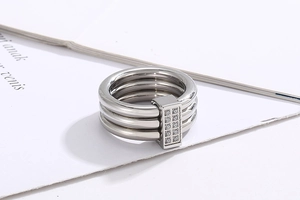 Detail of silver triple-band ring with CNC set zircons on a white paper background