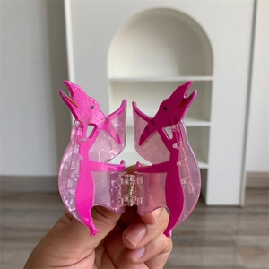 Close-up of a cute pink translucent pterosaur dinosaur acrylic hair claw clip for women