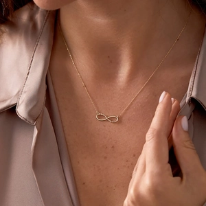 Elegant 18K gold infinity necklace with pavé cubic zirconia worn on a female model