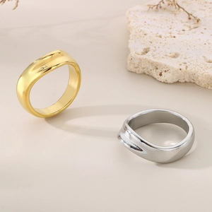 Dettaglio di anelli minimalisti oro e argento con texture ondulata su fondo in pietra